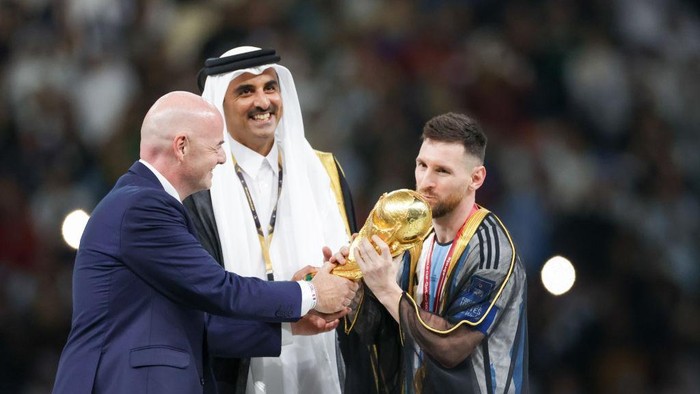 LUSAIL, QATAR - 2022/12/18: Gianni Infantino (president of FIFA), Emir of Qatar Tamim bin Hamad Al Thani hands a trophy to Lionel Messi (Argentina) are seen during the FIFA World Cup Qatar 2022 Final match between Argentina and France at Lusail Stadium. Final score: Argentina 3:3 (penalty 4:2) France. (Photo by Grzegorz Wajda/SOPA Images/LightRocket via Getty Images)