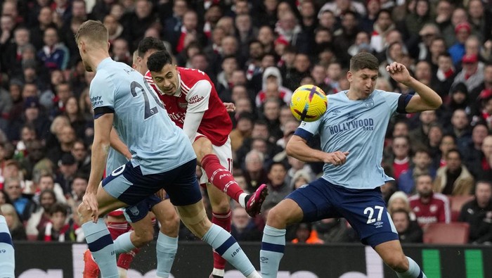 Arsenals Gabriel Martinelli, centre, shots on target as Brentfords Vitaly Janelt, right, tries to block during the English Premier League soccer match between Arsenal and Brentford at Emirates stadium in London, Saturday, Feb. 11, 2023. (AP Photo/Frank Augstein)