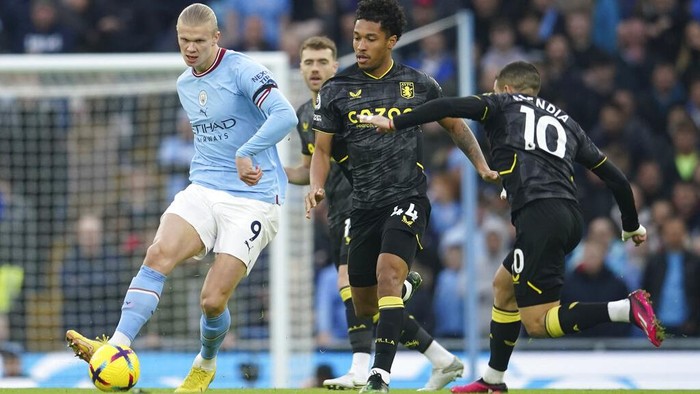 Manchester Citys Erling Haaland, left, kicks the ball ahead of Aston Villas Boubacar Kamara, centre, and Aston Villas Emiliano Buendia during the English Premier League soccer match between Manchester City and Aston Villa at the Etihad Stadium in Manchester, England, Sunday, Feb. 12, 2023. (AP Photo/Dave Thompson)