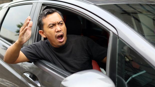 Angry asian man driving car. Arguing and gesturing with something in front his car