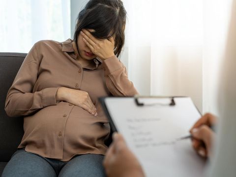 The pregnant mother is discussing depression symptoms during pregnancy with a specialist doctor or psychiatrist. The future mom is unhappy, worried, and stressed. Mental health concept