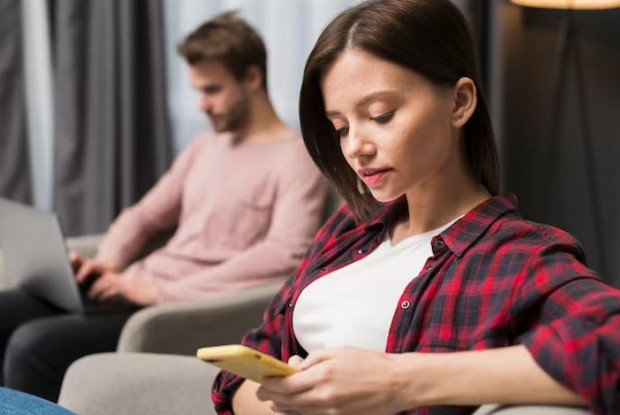 Perempuan dan laki-laki sedang bermain handphone sendiri-sendiri