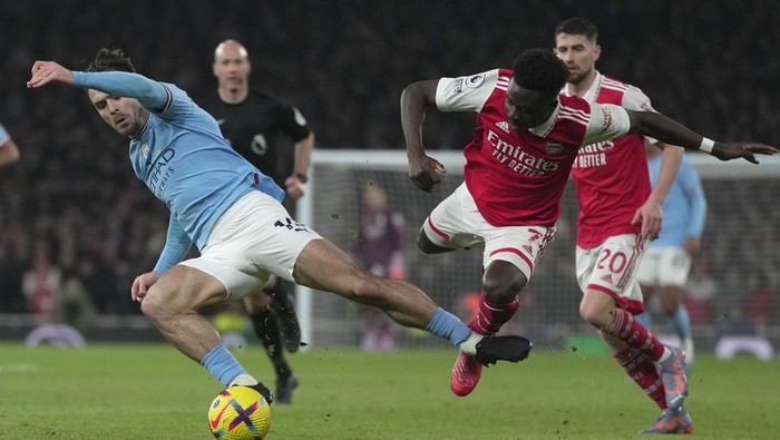 Manchester Citys Jack Grealish, left, in action against Arsenals Bukayo Saka during the English Premier League soccer match between Arsenal and Manchester City at the Emirates stadium in London, England, Wednesday, Feb.15, 2023. (AP Photo/Kin Cheung)