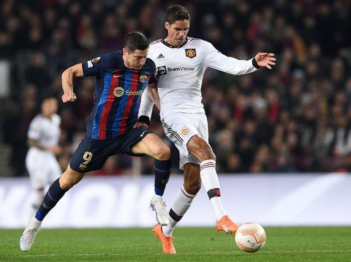 Barcelonas Polish forward Robert Lewandowski (L) fights for the ball with Manchester Uniteds French defender Raphael Varane during the UEFA Europa League round of 32 first-leg football match between FC Barcelona and Manchester United at the Camp Nou stadium in Barcelona, on February 16, 2023. (Photo by Josep LAGO / AFP) (Photo by JOSEP LAGO/AFP via Getty Images)