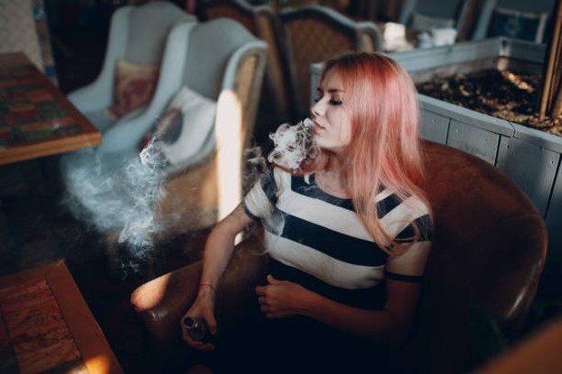 Foto seorang perempuan muda yang sedang merokok.