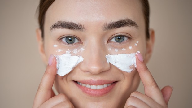 Sejumlah mitos kulit glowing/freepik/freepik Potret seorang perempuan tengah memakai sunscreen di wajahnya.