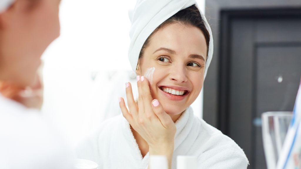 Potret seorang perempuan tengah memakai produk skincare.