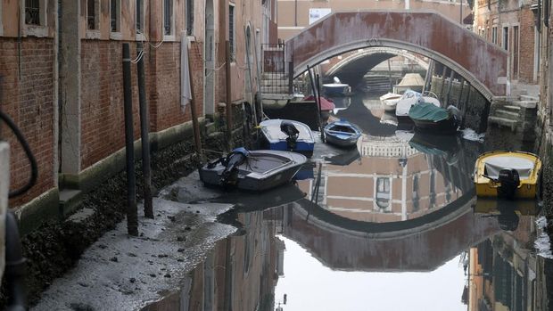 Boats are pictured in a canal during a severe low tide in the lagoon city of Venice, Italy, February 17, 2023. REUTERS/Manuel Silvestri
