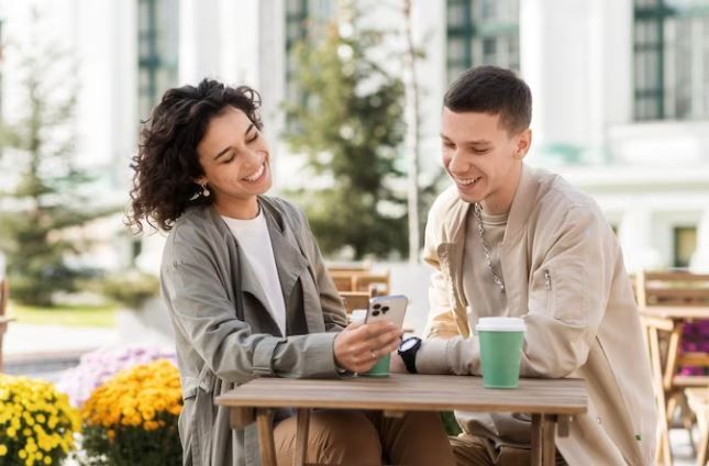 Perempuan dan laki-laki mengobrol sambil melihat handphone bersama