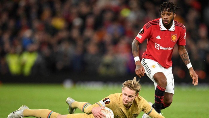 Barcelonas Dutch midfielder Frenkie de Jong (L) holds the ball after being tackled by Manchester Uniteds Brazilian midfielder Fred during the UEFA Europa league knockout round play-off second leg football match between Manchester United and FC Barcelona at Old Trafford stadium in Manchester, north west England, on February 23, 2023. (Photo by Oli SCARFF / AFP) (Photo by OLI SCARFF/AFP via Getty Images)