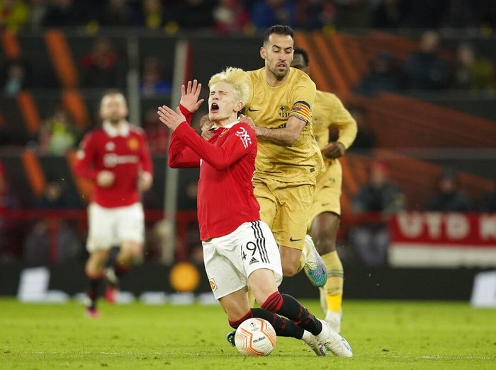 Manchester United's Alejandro Garnacho, right, is fouled by Barcelona's Sergio Busquets during the Europa League playoff second leg soccer match between Manchester United and Barcelona at Old Trafford stadium in Manchester, England, Thursday, Feb. 23, 2023. (AP Photo/Dave Thompson)