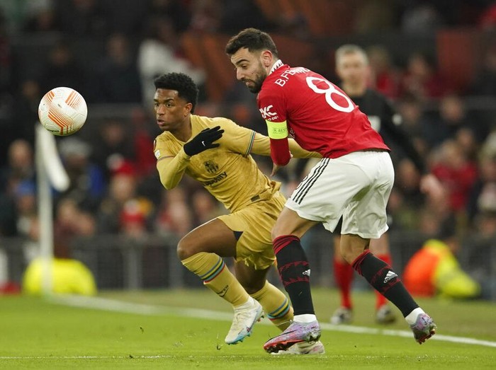 Barcelona's Alejandro Balde, left, is challenged by Manchester United's Bruno Fernandes during the Europa League playoff second leg soccer match between Manchester United and Barcelona at Old Trafford stadium in Manchester, England, Thursday, Feb. 23, 2023. (AP Photo/Dave Thompson)