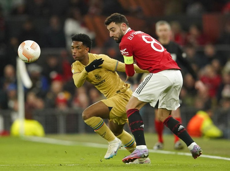 Barcelona's Alejandro Balde, left, is challenged by Manchester United's Bruno Fernandes during the Europa League playoff second leg soccer match between Manchester United and Barcelona at Old Trafford stadium in Manchester, England, Thursday, Feb. 23, 2023. (AP Photo/Dave Thompson)