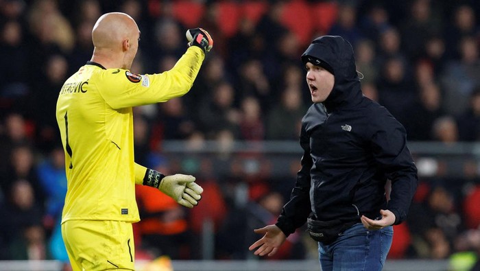 Soccer Football - Europa League - Play-Off Second Leg - PSV Eindhoven v Sevilla - Philips Stadion, Eindhoven, Netherlands - February 23, 2023 Pitch invader clashes with Sevillas Marko Dmitrovic REUTERS/Piroschka Van De Wouw  REFILE - CORRECTING ID