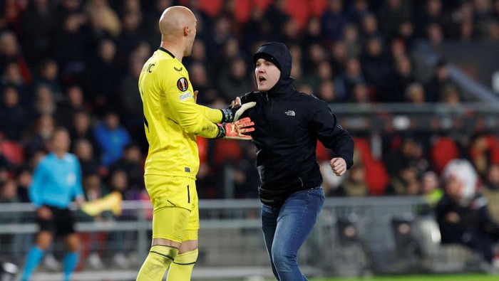 Marko Dmitrovic vs Penyusup Lapangan Soccer Football - Europa League - Play-Off Second Leg - PSV Eindhoven v Sevilla - Philips Stadion, Eindhoven, Netherlands - February 23, 2023 Pitch invader clashes with Sevilla's Marko Dmitrovic REUTERS/Piroschka Van De Wouw REFILE - CORRECTING ID