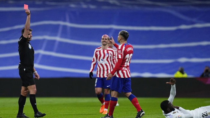 Referee Jesus Gil Manzano, left, shows a red card to Atletico Madrids Angel Correa after he fouled Real Madrids Rodrygo, bottom, during a Spanish La Liga soccer match between Real Madrid and Atletico Madrid at the Santiago Bernabeu stadium in Madrid, Spain, Saturday, Feb. 25, 2023. (AP Photo/Manu Fernandez)