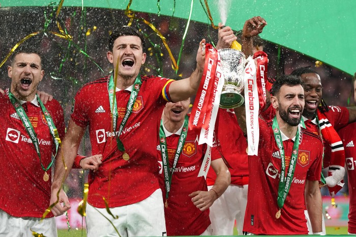 Manchester Uniteds Bruno Fernandes, centre right, and Harry Maguire, second from left, hold the trophy during celebration as they won the English League Cup final soccer match between Manchester United and Newcastle United at Wembley Stadium in London, Sunday, Feb. 26, 2023. (AP Photo/Alastair Grant)