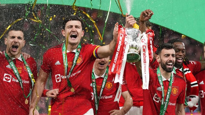 Manchester United's Bruno Fernandes, centre right, and Harry Maguire, second from left, hold the trophy during celebration as they won the English League Cup final soccer match between Manchester United and Newcastle United at Wembley Stadium in London, Sunday, Feb. 26, 2023. (AP Photo/Alastair Grant)