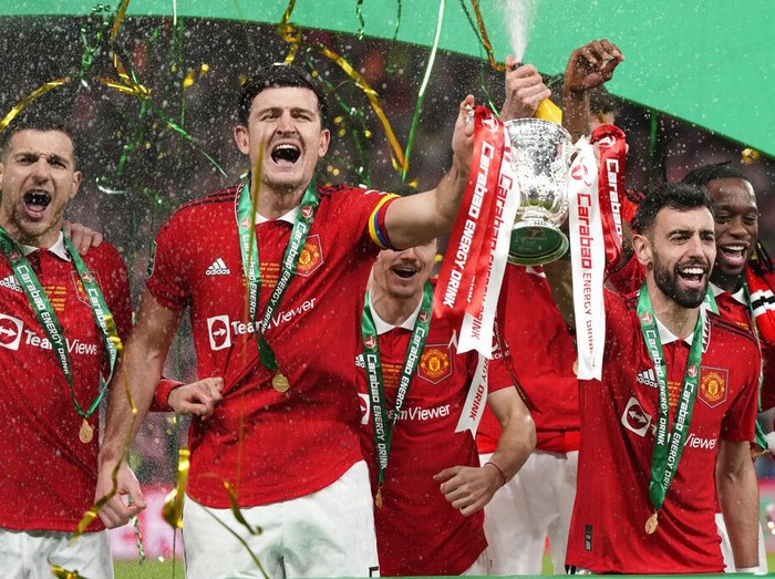 Manchester United's Bruno Fernandes, centre right, and Harry Maguire, second from left, hold the trophy during celebration as they won the English League Cup final soccer match between Manchester United and Newcastle United at Wembley Stadium in London, Sunday, Feb. 26, 2023. (AP Photo/Alastair Grant)