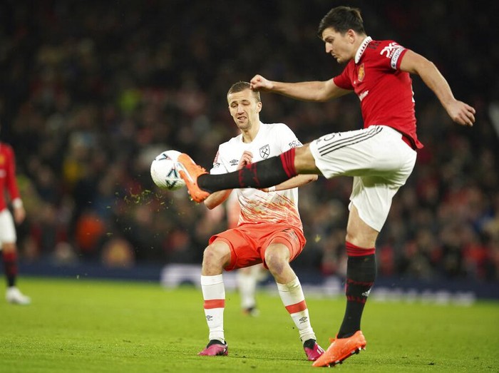 MU Menang Dramatis Atas West Ham, Melaju ke Perempatfinal Piala FA Manchester United's Harry Maguire, right, kicks the ball ahead of West Ham's Tomas Soucek during the English FA Cup fifth round soccer match between Manchester United and West Ham at Old Trafford stadium in Manchester, England, Wednesday, March 1, 2023. (AP Photo/Dave Thompson)