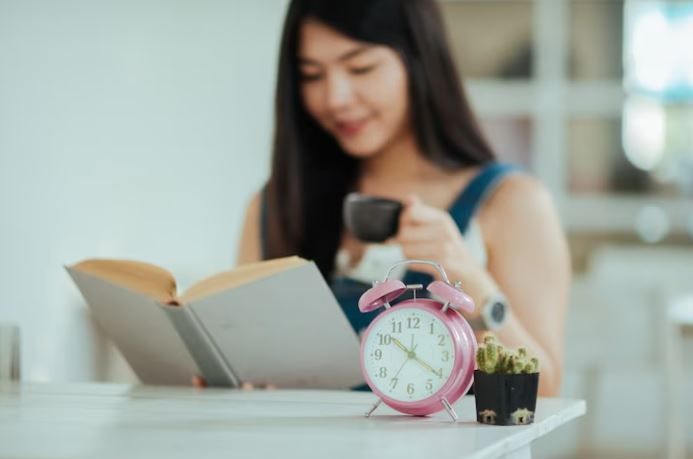 Perempuan sedang duduk, membaca sambil meminum kopi