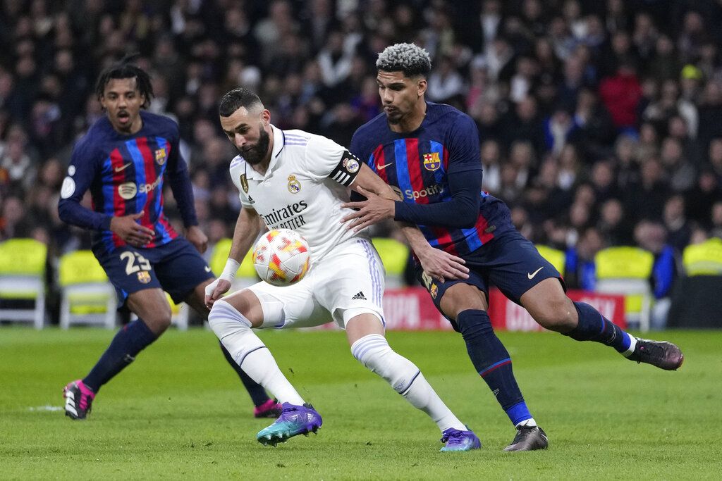 Real Madrid's Karim Benzema, centre, controls the ball as he is challenged by Barcelona's Ronald Araujo, right, and Barcelona's Jules Kounde during the Spanish Copa del Rey semi final, first leg soccer match between Real Madrid and Barcelona at Santiago Bernabeu stadium in Madrid, Spain, Thursday, March 2, 2023. (AP Photo/Bernat Armangue)