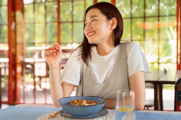 Woman is enjoying her meal with chopsticks in hand