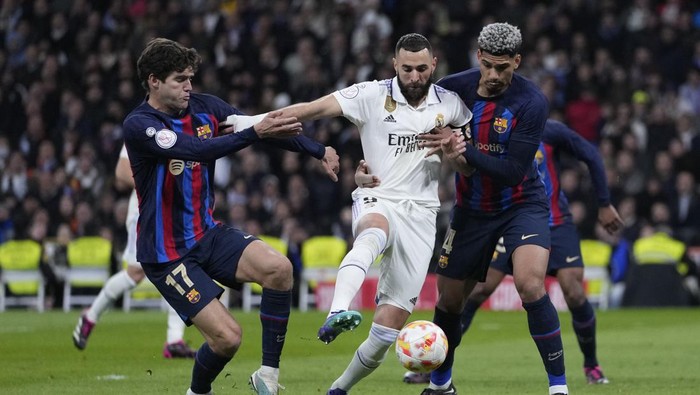 Real Madrids Karim Benzema, centre, fights for the ball with Barcelonas Ronald Araujo, right, and Barcelonas Marcos Alonso during the Spanish Copa del Rey semi final, first leg soccer match between Real Madrid and Barcelona at Santiago Bernabeu stadium in Madrid, Spain, Thursday, March 2, 2023. (AP Photo/Bernat Armangue)