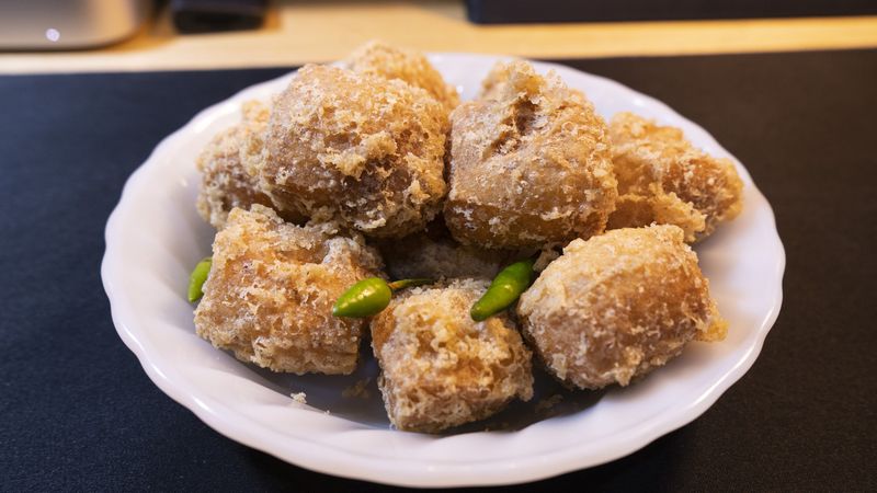 Fried sumedang tofus (Tahu goreng sumedang) with cayenne pepper served on a white plate.