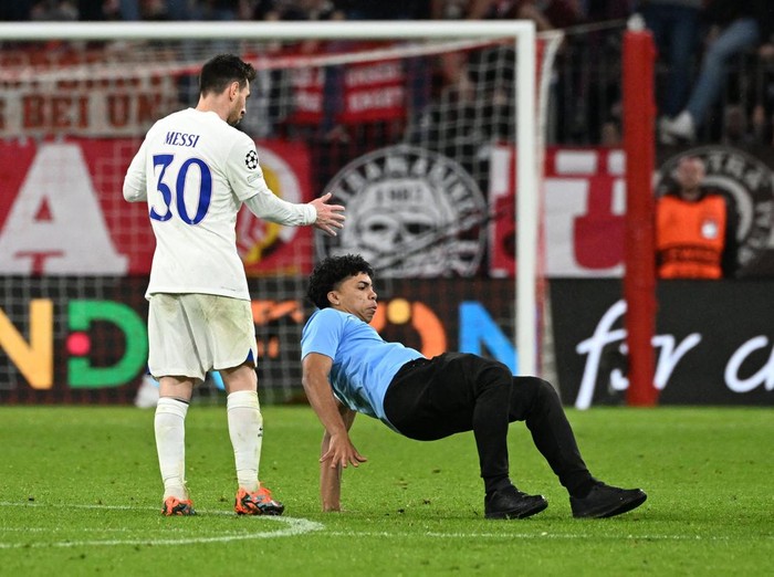 Soccer Football - Champions League - Round of 16 - Second Leg - Bayern Munich v Paris St Germain - Allianz Arena, Munich, Germany - March 8, 2023  A pitch invader is seen as Paris St Germain's Lionel Messi looks dejected after the match REUTERS/Angelika Warmuth