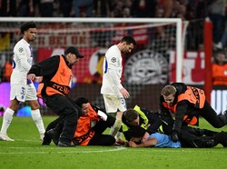 Karena si penyusup lapangan tampak masih belum menyerah dengan niatan awal memeluk Messi, tindakan antisipasi ekstra pun dilakukan. Lihat saja berapa banyak petugas yang mengerumuninya! Foto: REUTERS/ANGELIKA WARMUTH  