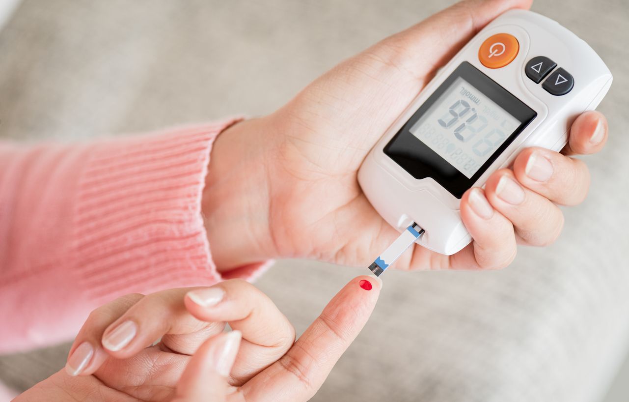 Close up woman hands checking blood sugar level by glucose meter for diabetes tester using as medicine, glycemia, healthcare and medical concept.