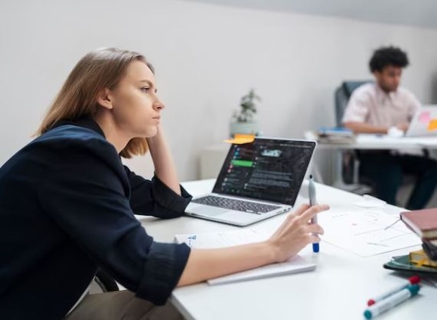 Perempuan sedang berpikir di depan laptop