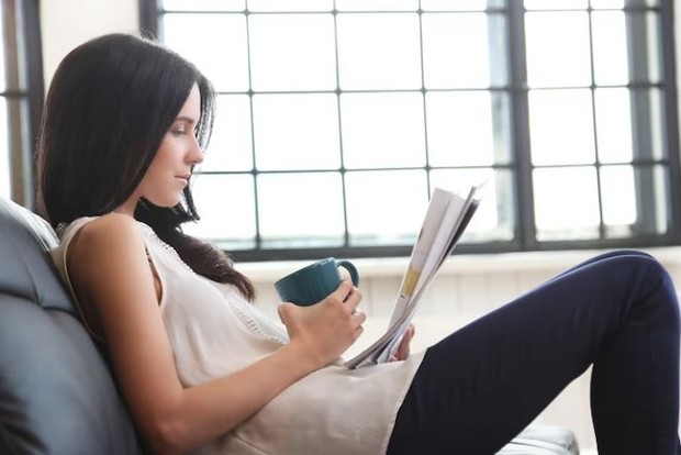 Perempuan sedang bersandar santai sambil membaca