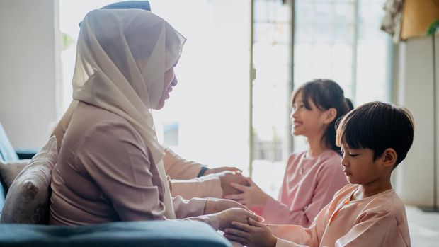 Malay Muslim children in traditional clothings asking forgiveness to their parents during Hari Raya Aidilfitri celebration