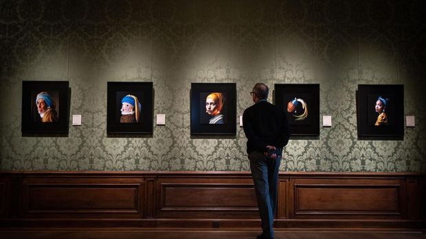 A museum's staff looks at an image (C) designed with artificial intelligence by Berlin-based digital creator Julian van Dieken, inspired by Johannes Vermeer's painting 