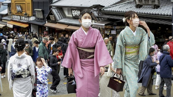 Visitors walk along a sightseeing destination in Kyoto, western Japan Monday, March 13, 2023. Japan on Monday dropped its request for people to wear masks after three years, but hardly anything changed in the country that has had an extremely high regard for their effectiveness at anti-virus protection. (Kyodo News via AP)