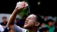 Seorang anak berlaga menyiramkan kepalanya dengan air layaknya pesepakbola idamannya.