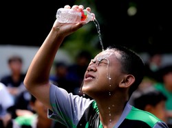 Seorang anak berlaga menyiramkan kepalanya dengan air layaknya pesepakbola idamannya.