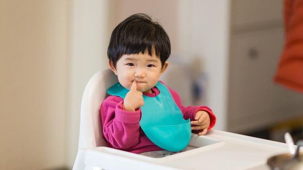 Cute baby Sitting in a high chair waiting for to eat dinner