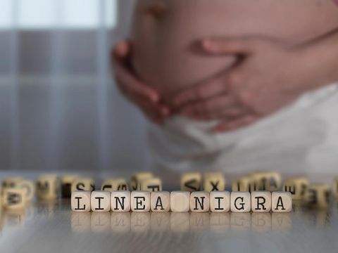 Words LINEA NIGRA for Black Line composed of wooden letters. Pregnant woman in the backgroundIlustrasi Linea nigra pada ibu hamil