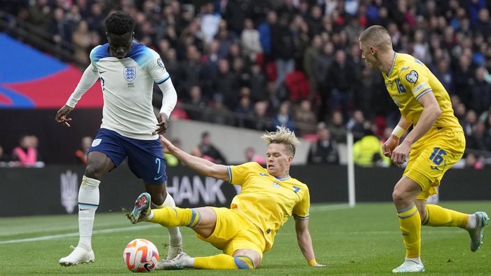 Englands Bukayo Saka, left,challenges for the ball with Ukraines Mykhailo Mudryk, centre, and Ukraines Vitaliy Mykolenko, right, during the Euro 2024 group C qualifying soccer match between England and Ukraine at Wembley Stadium in London, Sunday, March 26, 2023. (AP Photo/Alastair Grant)