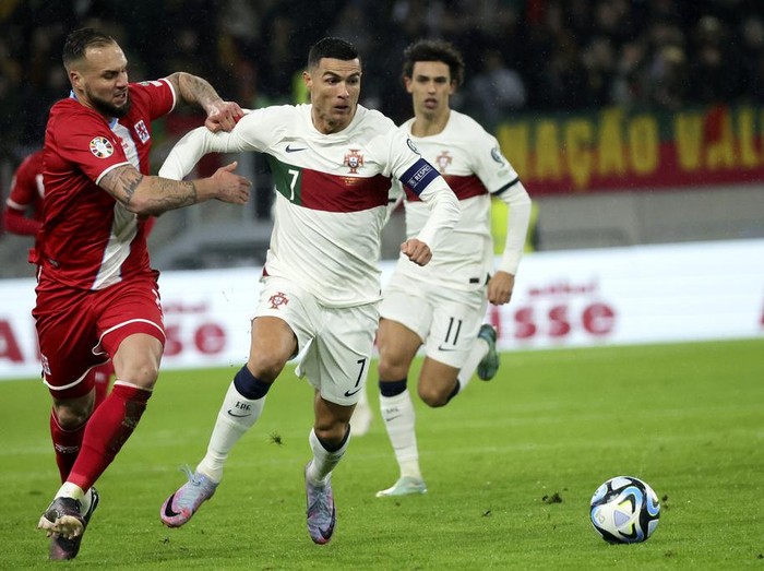 Portugal's Cristiano Ronaldo, center, fights for the ball against Luxembourg's Maxime Chanot during the Euro 2024 group J qualifying soccer match between Luxembourg and Portugal at the Stade de Luxembourg in Luxembourg, Sunday, March 26, 2023. (AP Photo/Olivier Matthys)
