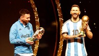 Seperti tidak mau kalah dengan patung yang menjadi kembarannya, Messi pun ikut menimbang trofi Piala Dunia. Foto: REUTERS/CESAR OLMEDO