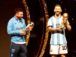 Seperti tidak mau kalah dengan patung yang menjadi kembarannya, Messi pun ikut menimbang trofi Piala Dunia. Foto: REUTERS/CESAR OLMEDO