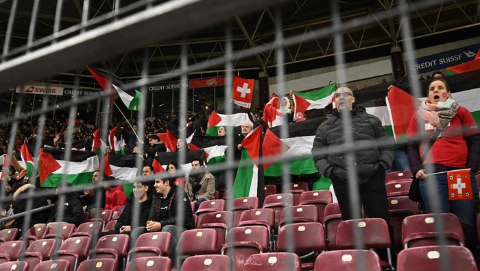 Palestinian demonstrators hold palestinian flags during the UEFA Euro 2024 qualification football match between Switzerland and Israel at Stade de Geneve in Geneva on March 28, 2023. (Photo by Fabrice COFFRINI / AFP) (Photo by FABRICE COFFRINI/AFP via Getty Images)