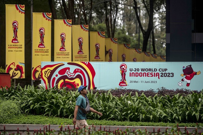 Warga berjalan di dekat papan promosi Piala Dunia U-20 Indonesia 2023 di kawasan GBK Arena, Jakarta, Kamis (30/3/2023). FIFA resmi mencabut status Indonesia sebagai tuan rumah untuk gelaran Piala Dunia U-20 2023 mendatang.