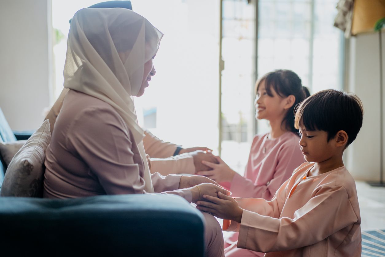 Malay Muslim children in traditional clothings asking forgiveness to their parents during Hari Raya Aidilfitri celebration