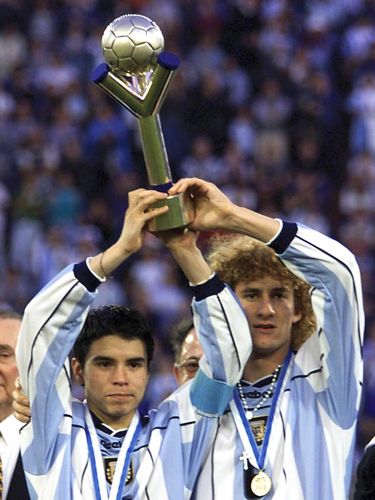 Javier Saviola (L) and Fabricio Coloccini of Argentina raise the World Youth Soccer Championship trophy 08 July 2001 after winning the final game of the championship against Ghana at the Jose Amalfitani stadium in Buenos Aires, Argentina. Argentina won the game 3-0.   AFP PHOTO/Antonio SCORZA / AFP PHOTO / -        (Photo credit should read -/AFP via Getty Images)