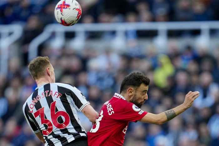 Newcastles Sean Longstaff, left, jumps for the ball with Manchester Uniteds Bruno Fernandes during the English Premier League soccer match between Newcastle United and Manchester United, at St. James Park stadium in Newcastle, England, Sunday, April 2, 2023. (AP Photo/Jon Super)